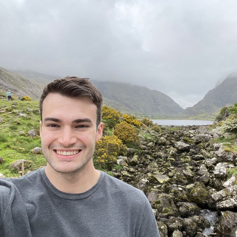 Jack in a valley of mossy boulders, with mountains in cloud behind him